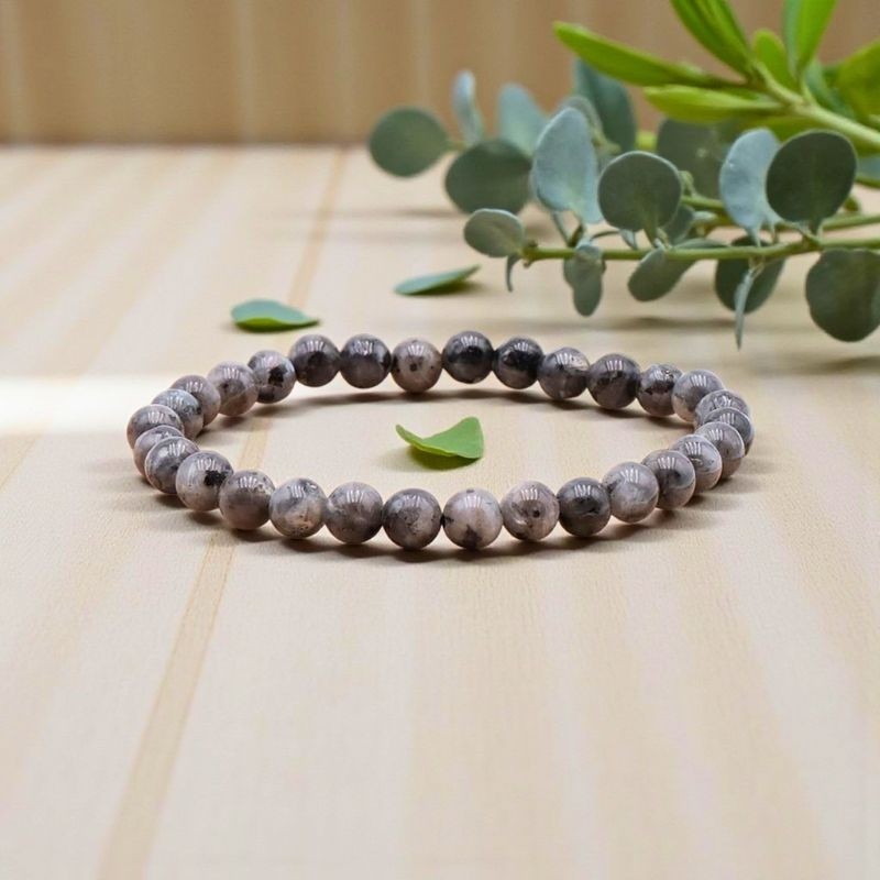 Bracelet en Larvikite présenté sur un fond en bois clair, mettant en valeur ses reflets minéraux caractéristiques